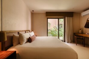 Ein Hotelzimmer mit einem großen Bett, einem Schreibtisch und Blick auf Grünfläche.