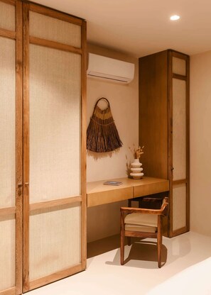 Ein Zimmer mit einem Holztisch, einem Stuhl, einer Wandklimaanlage und einem Wandbehang aus Gewebe.