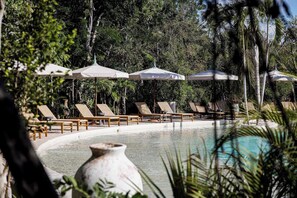 A poolside area with lounge chairs and umbrellas, surrounded by trees. - Aflora Moon 3 bd First FloorBeach Club + Breakfast (Tulum)