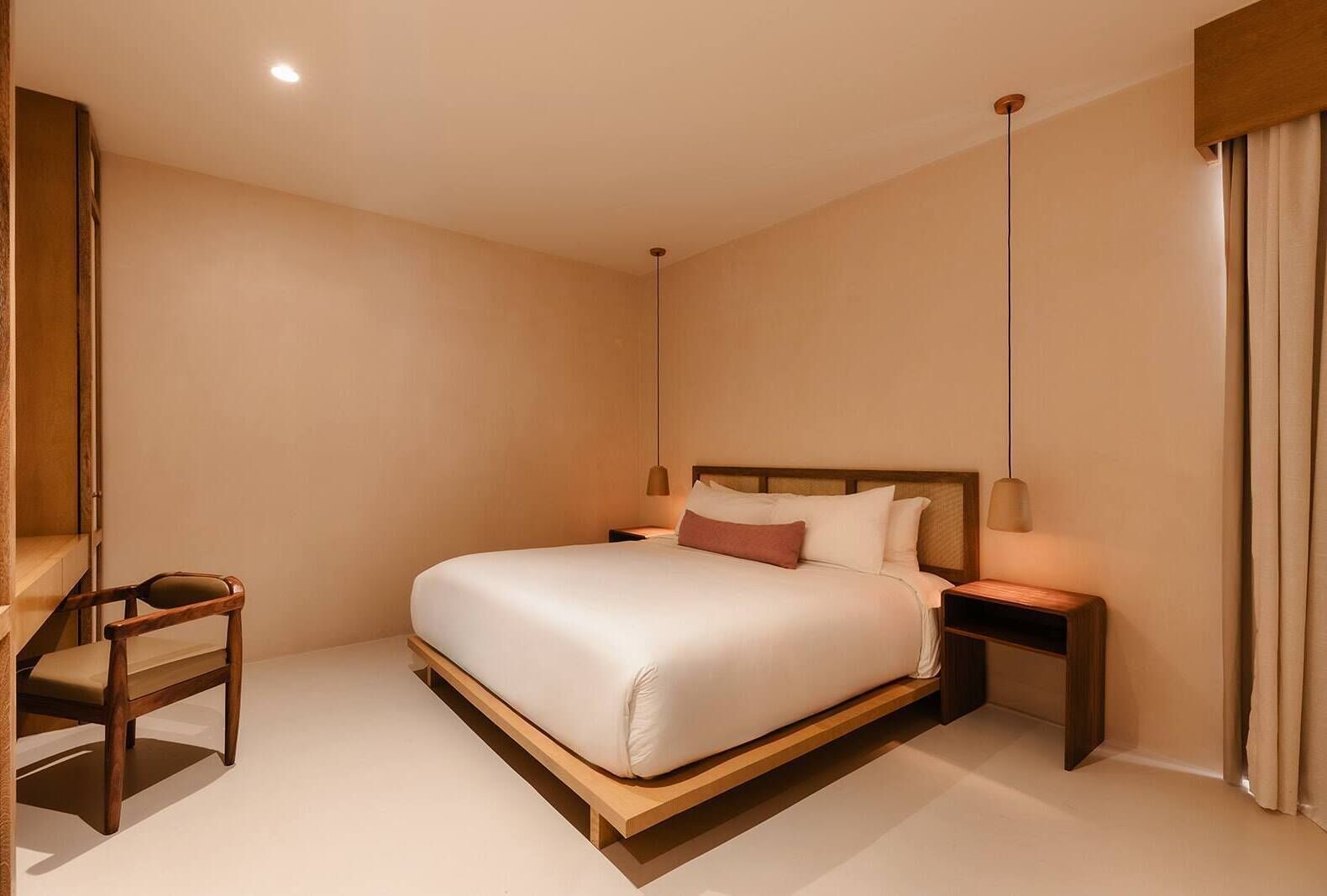 A modern bedroom with a large bed, a wooden nightstand, a bedside table, and a chair.