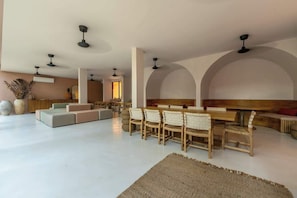 A spacious living area with a long dining table, multiple seating options, and ceiling fans. - Aflora Onyx Loft L224 Beach Club  + Breakfast (Tulum)