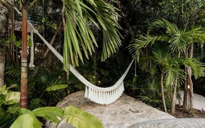 A hammock in a lush garden with various tropical plants and a stone pathway. - Aflora Onyx Loft L224 Beach Club  + Breakfast (Tulum)