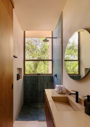 Ein modernes Badezimmer mit Dusche, Waschbecken und einem großen Spiegel.