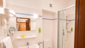Et moderne badeværelse med vask, toilet og brusekabine med glasvægge.