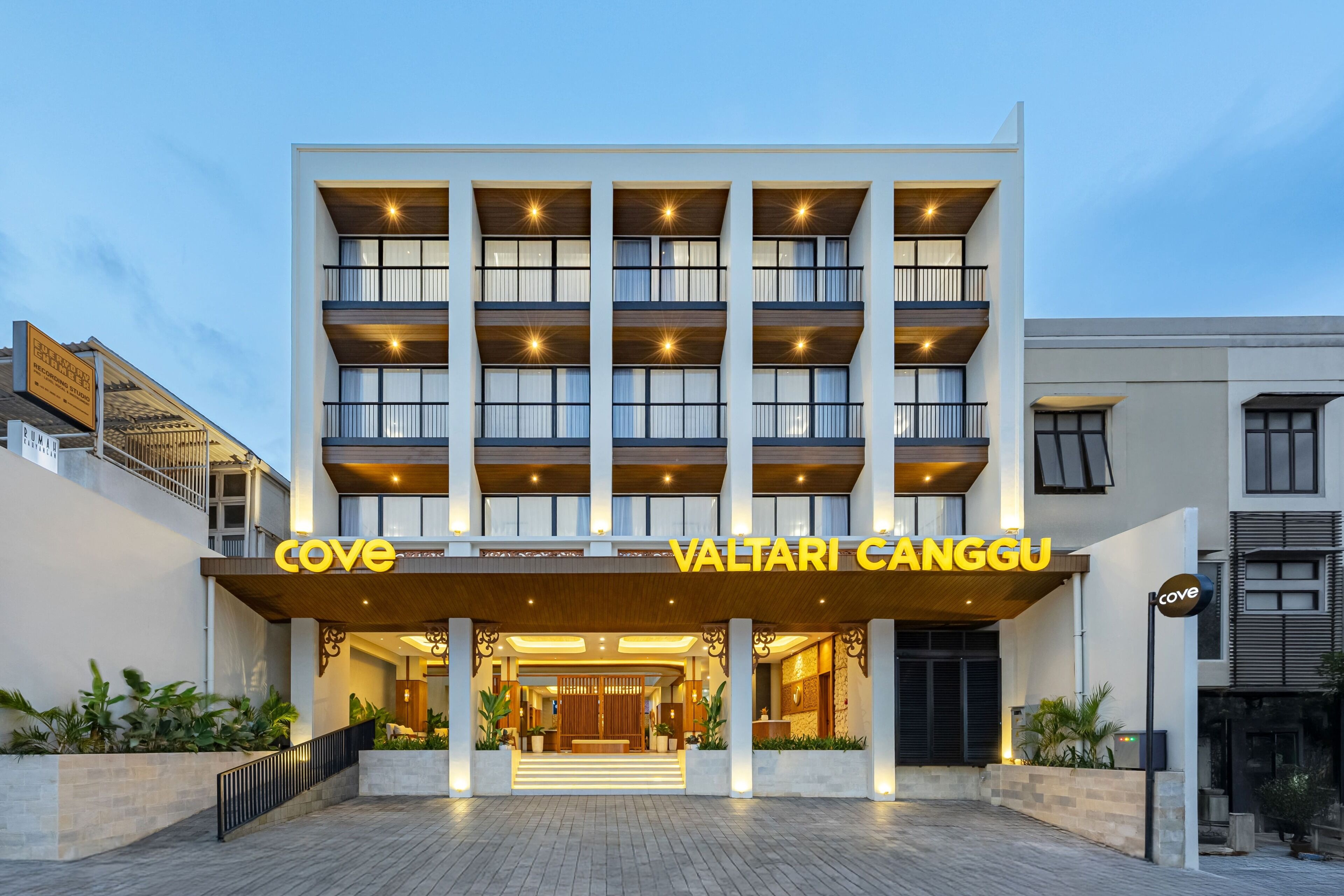 Un hotel de varios pisos con fachada moderna, entrada destacada y señalización iluminada.