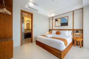 Una habitación de hotel moderna con una cama grande, un armario de madera, un baño con espejo y una lámpara en el techo.