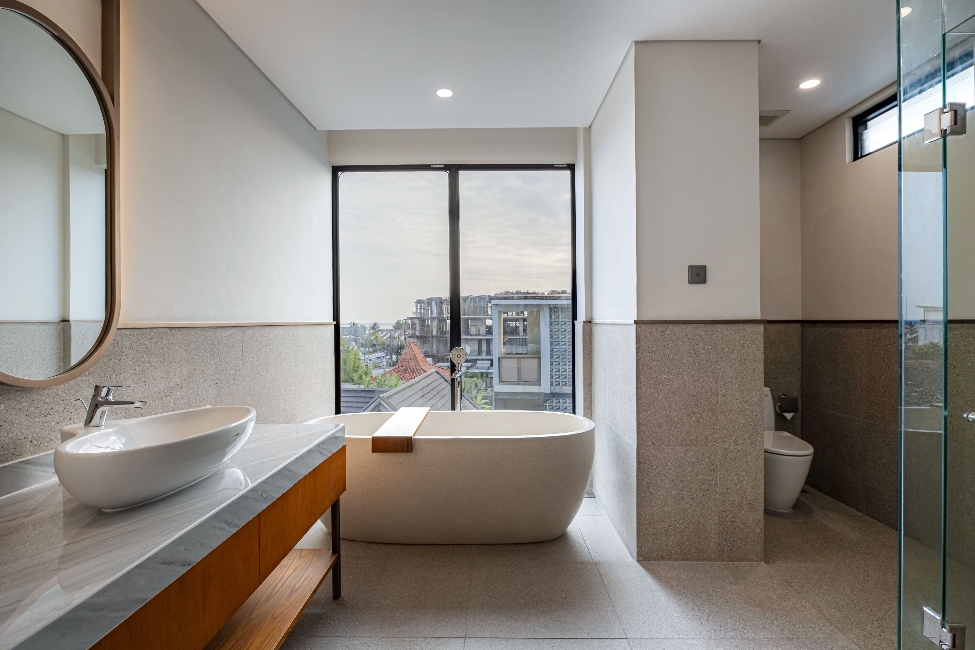 Un baño moderno con una bañera independiente, un tocador doble y un ventanal con vistas a la ciudad.