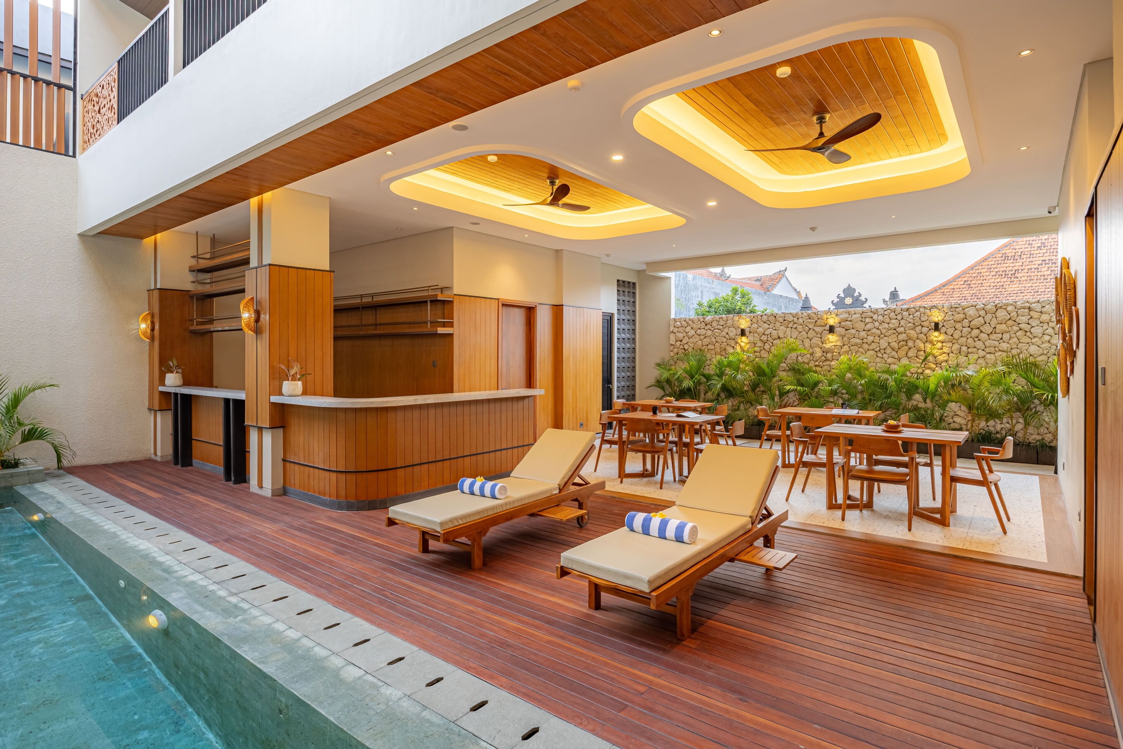 Ein moderner Poolbereich im Freien mit Holzliegen und einer Bar.