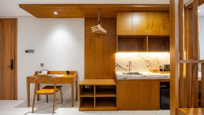 Une cuisine compacte avec des meubles en bois, un plan de travail en marbre et un luminaire suspendu.