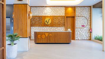 Un área de recepción con un mostrador de madera, pared de piedra y una lámpara en el techo.