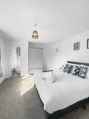 A bedroom with a bed, a wardrobe, a shower, and a hanging light fixture.