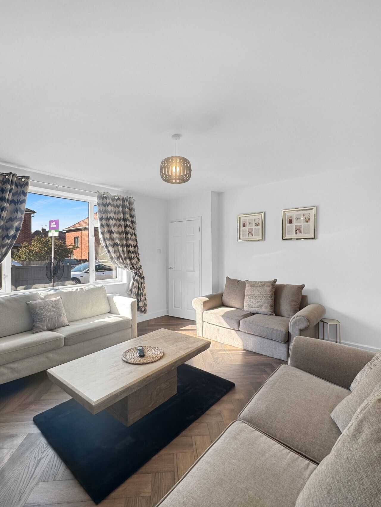 A modern living room with a sofa set, a coffee table, and a hanging light fixture.