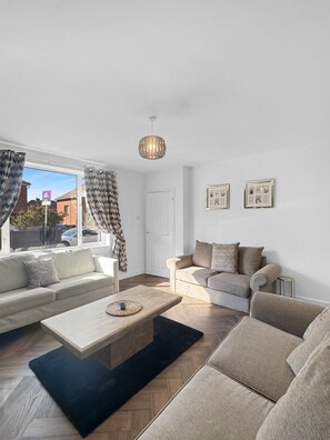 A modern living room with a sofa set, a coffee table, and a hanging light fixture.
