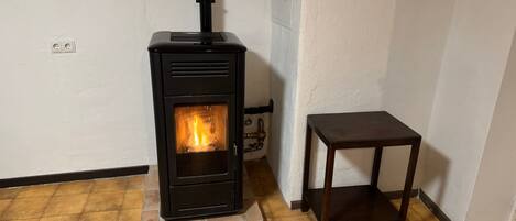 Ein Kaminofen mit Schornstein, ein kleiner Holztisch und ein Fliesenboden.