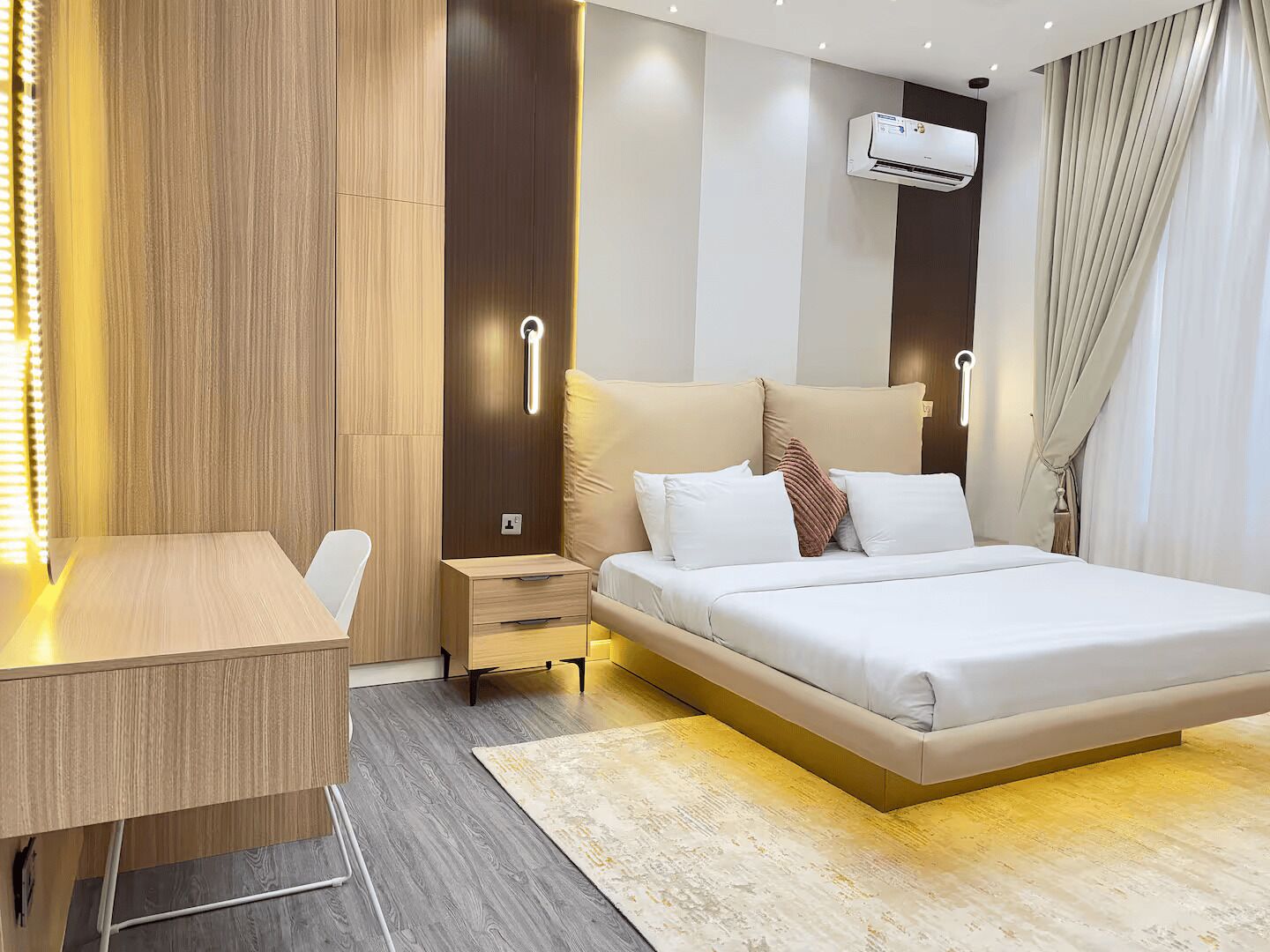 Ein modernes Hotelzimmer mit einem Bett, Nachttischen, einem Schreibtisch und einer Klimaanlage.