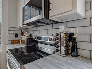 A kitchen with a stainless steel stove, a wine rack, and a microwave. - Belltown House at Airline Trail (East Hampton)