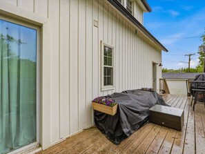 Un espace extérieur abrité, avec une table et des chaises, une fenêtre et une terrasse en bois.