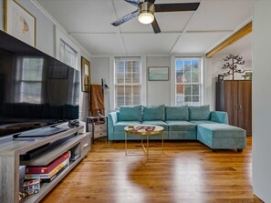 Un salon comprenant un canapé d’angle, une table basse, un téléviseur et un ventilateur de plafond.