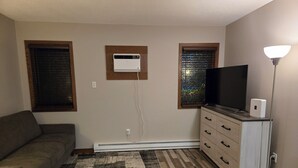 Una sala de estar con un sofá, un televisor de pantalla plana, un calentador y una lámpara.
