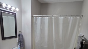 Baño con lavamanos, espejo, inodoro y cortina de ducha.