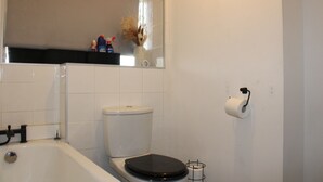 A bathroom with a toilet, a bathtub, and a toilet paper holder.