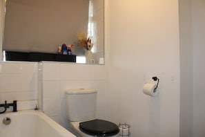 A bathroom with a toilet, a bathtub, and a toilet paper holder. - Wimbledon Gem 2BR Free Parking Near Station (London)