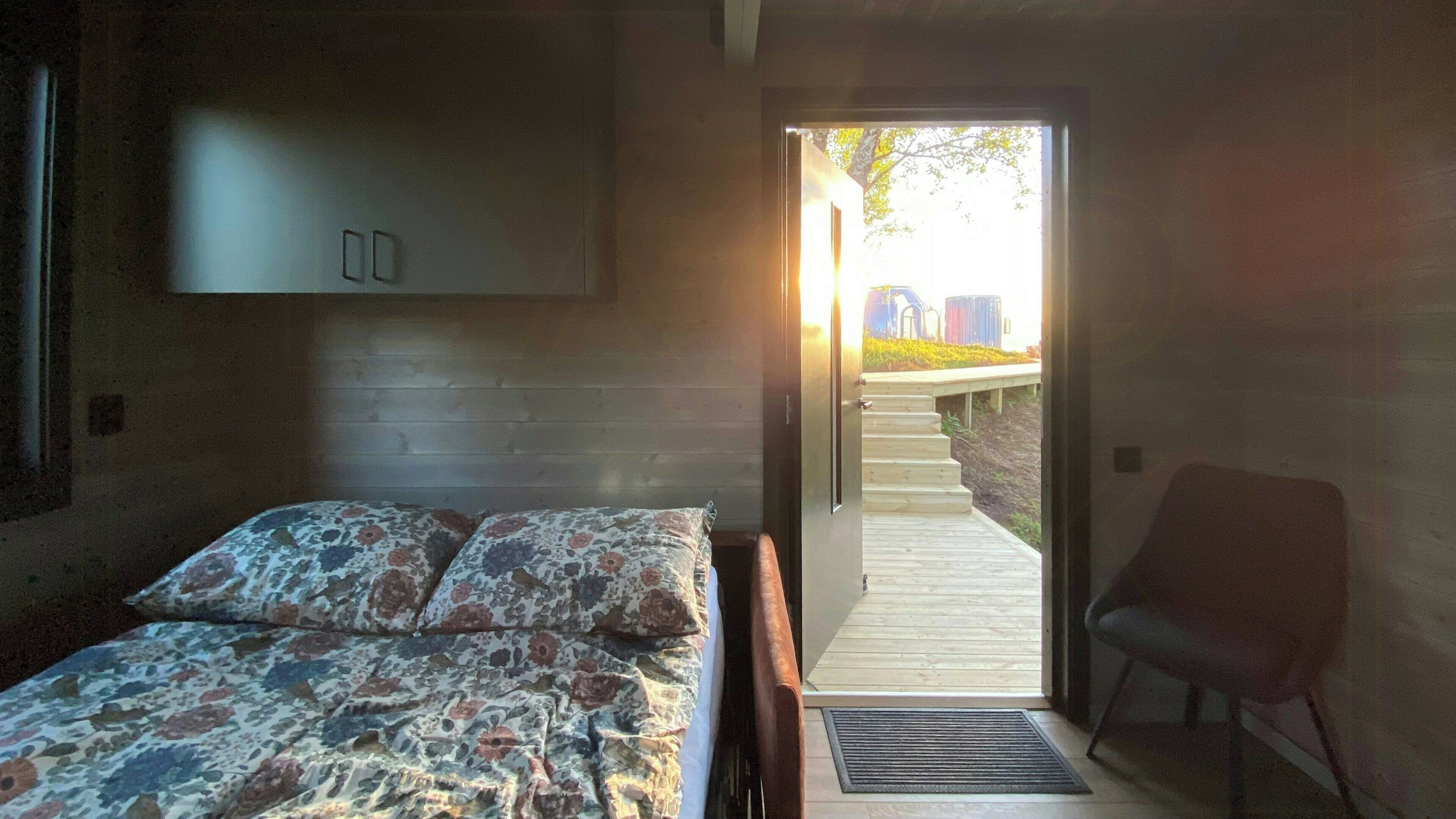 A bedroom with a bed, a chair, and a door leading to an outdoor area.