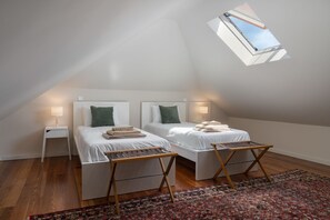 Ein Schlafzimmer mit zwei Betten, einem kleinen Tisch, einem Nachttisch und einem gemusterten Teppich.