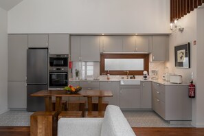 Eine moderne Küche mit grauen Schränken, einem Holztisch und einem eingebauten Backofen.