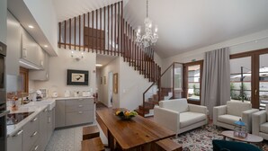 A modern kitchen with a wooden staircase, a dining area with a wooden table, and a living room with a sofa and armchairs. - Villa with pool in Machico near beach|Casa da Tia (Machico)