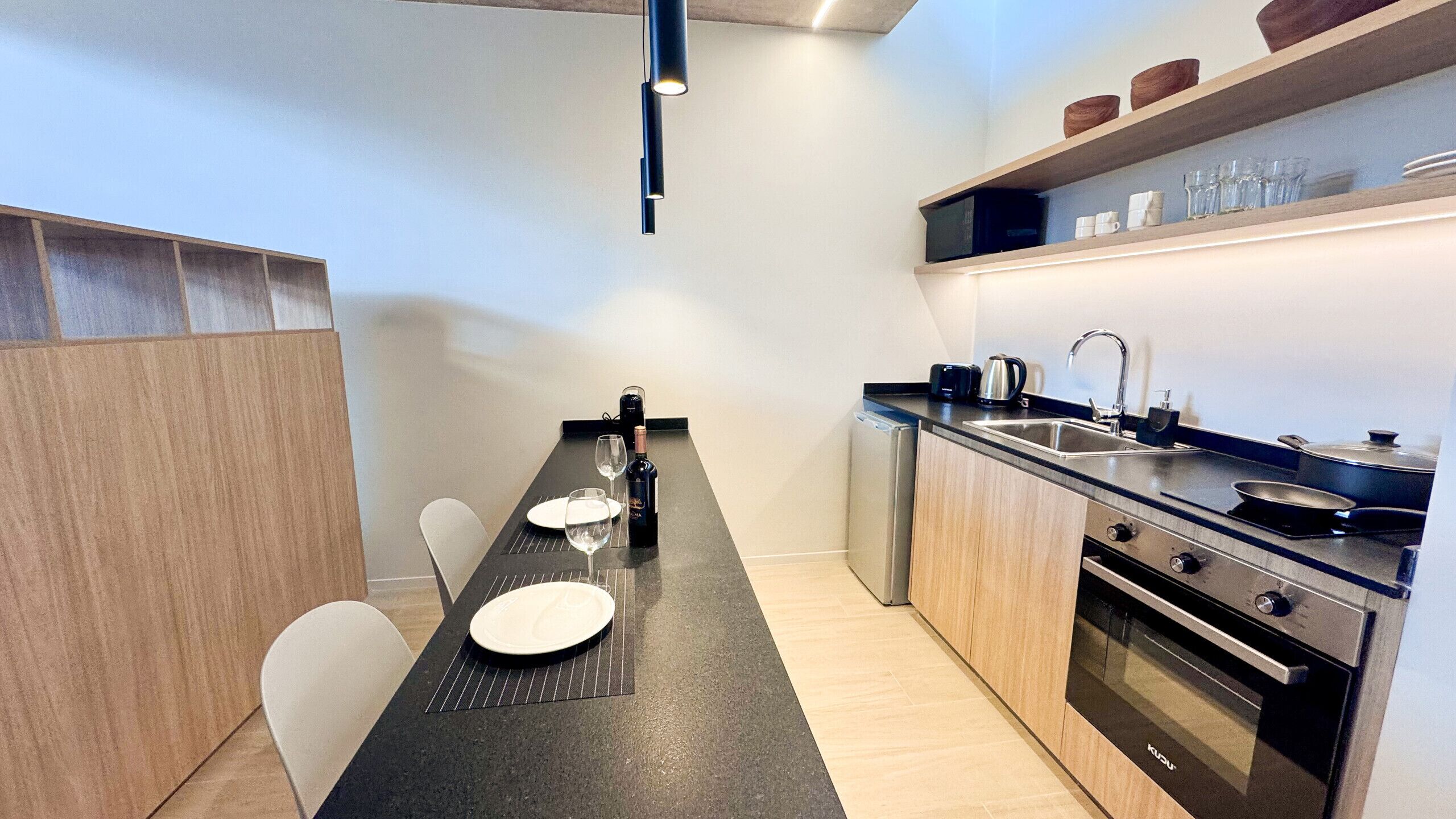 Una cocina moderna con comedor, electrodomésticos de acero inoxidable y encimera negra.