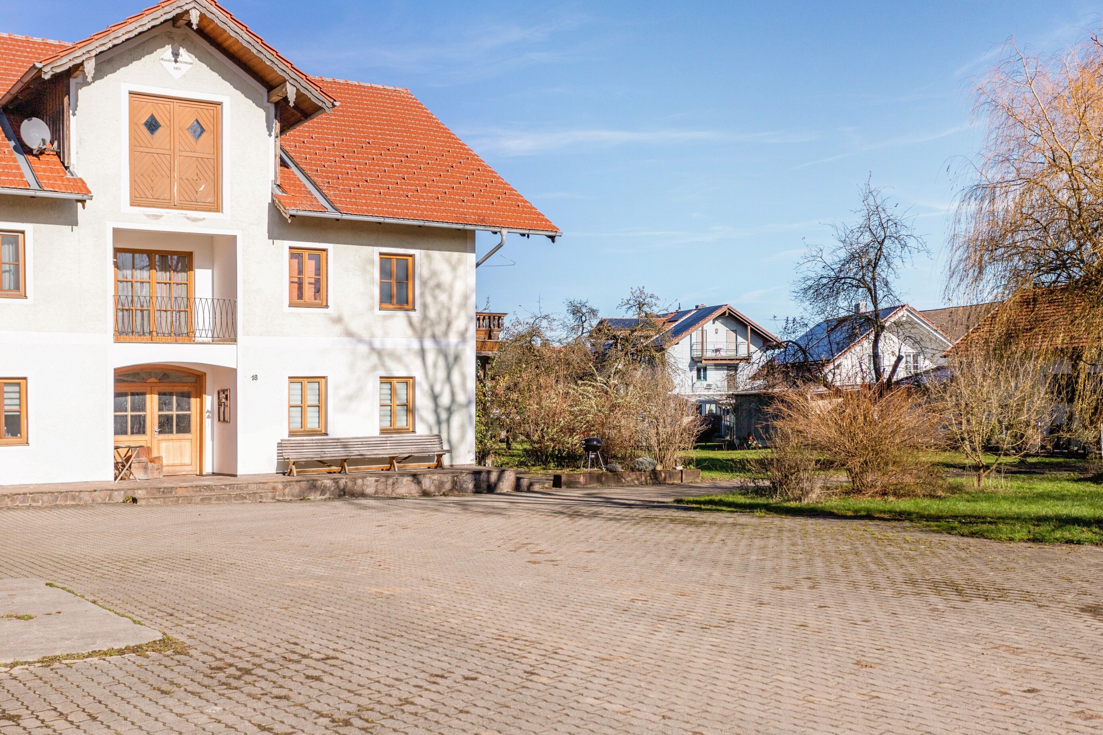 Ein großes, weißes Gebäude mit rotem Ziegeldach, zahlreichen Fenstern und einem gepflasterten Innenhof.