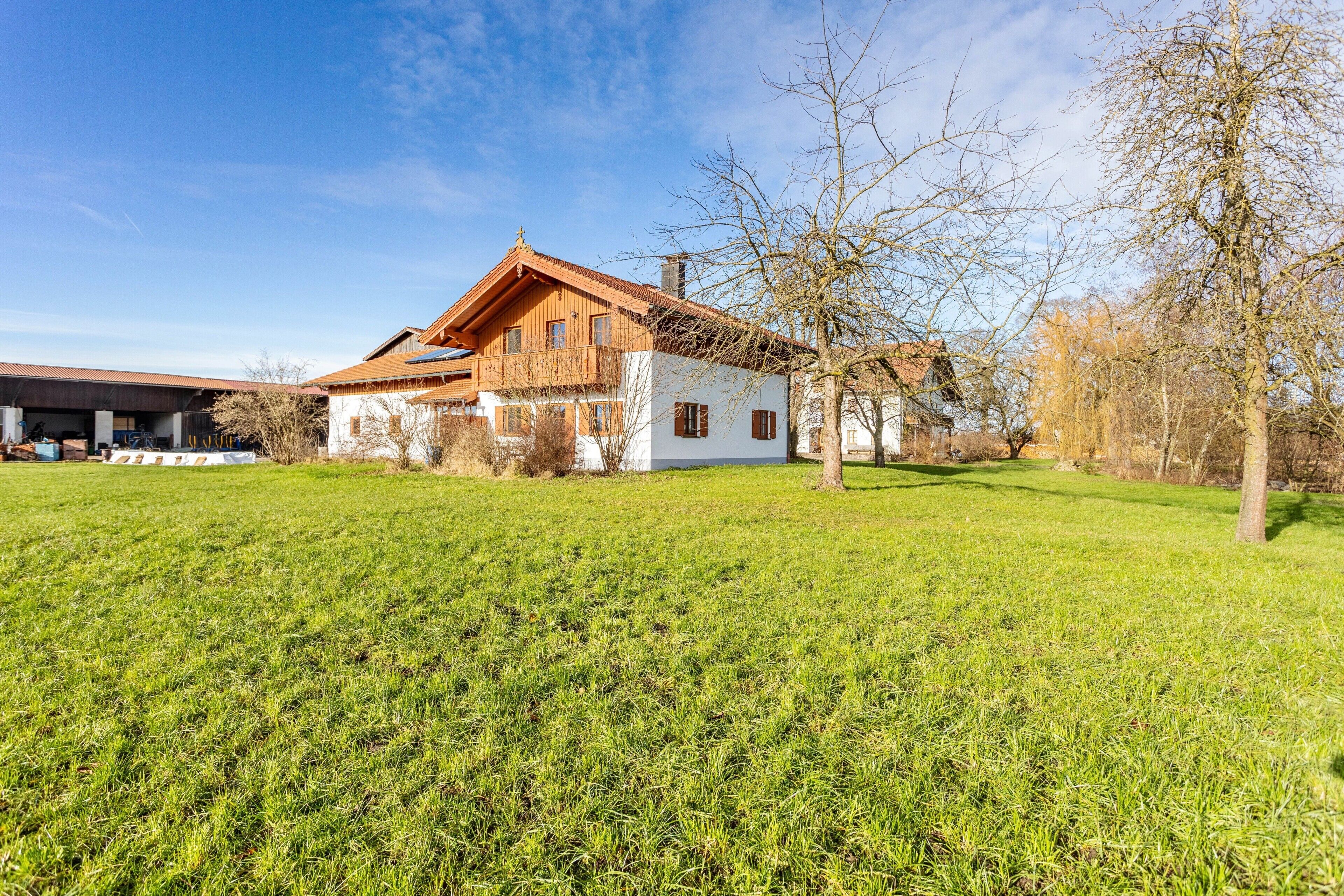 Ein zweistöckiges Holzhaus mit geneigtem Dach, umgeben von einem gepflegten Rasen.