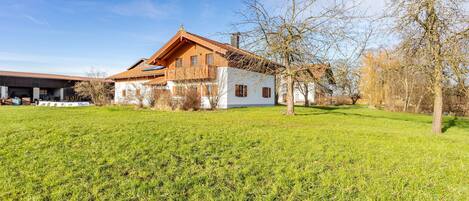 Ein zweistöckiges Holzhaus mit geneigtem Dach, umgeben von einem gepflegten Rasen.