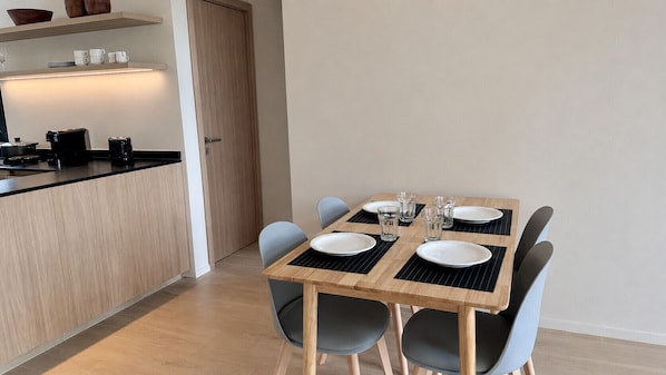 A modern dining area with a wooden table, black placemats, and grey chairs.