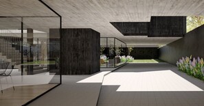Un espacio arquitectónico moderno con techo de hormigón, paredes de vidrio y un jardín central.