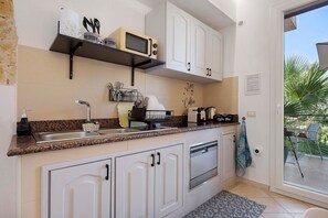 Cuina amb armaris blancs, microones, cafetera i un rentaplat.