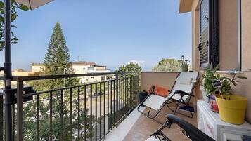 Un balcone con vista sulla città, una sedia, un tavolino e una pianta in vaso.