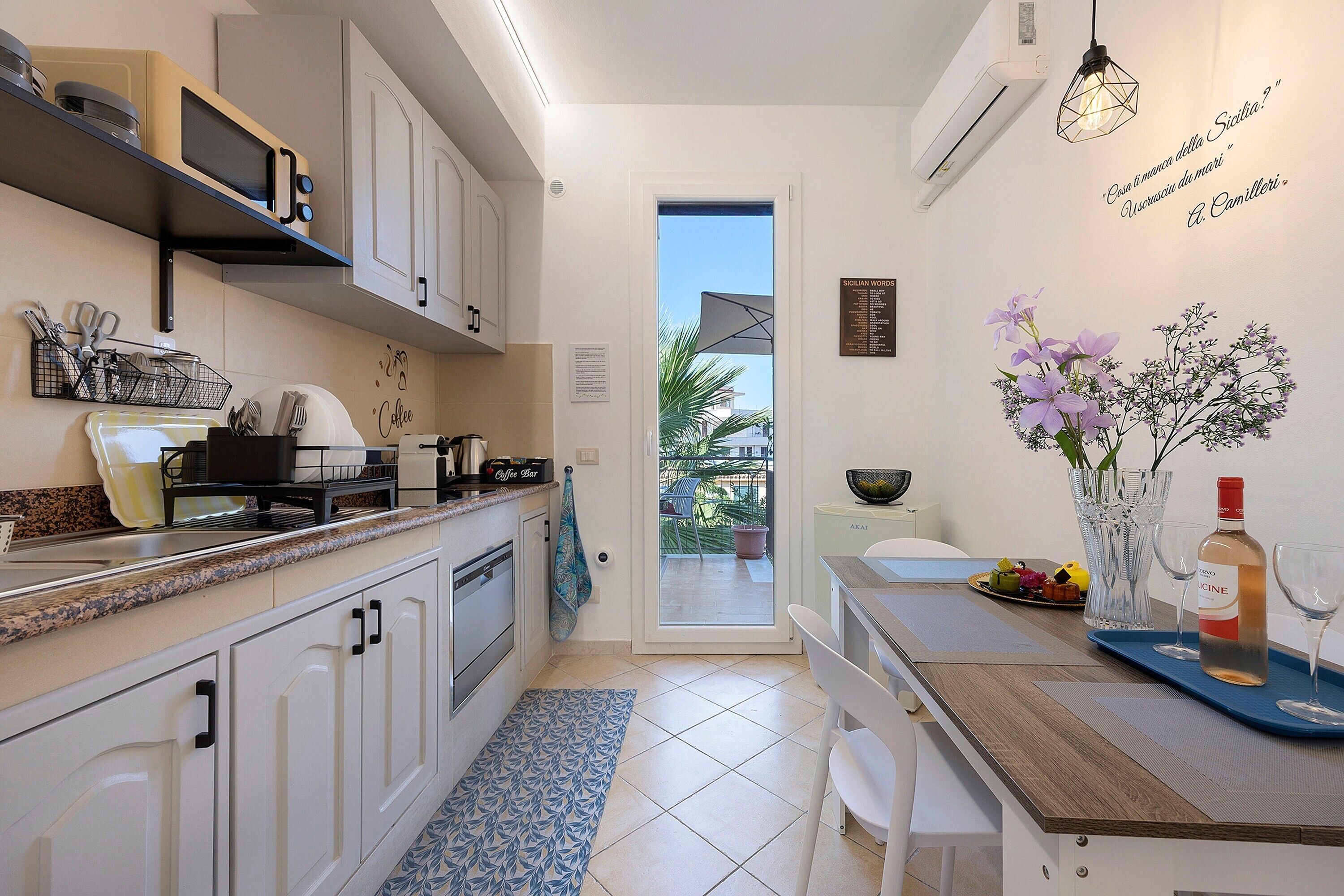 A modern kitchen with white cabinets, a coffee bar, and a dining area with a table set for two.
