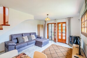 A modern living room with a grey sofa, a wooden cabinet, and a television. - Cubo's El Refugio de Elviria House / communal pool / air conditioning / terrace / free Wi-Fi (Marbella)