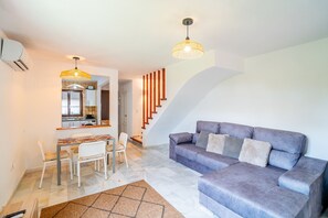 A living room with a sofa, a dining area with a table and chairs, a kitchen with a refrigerator, and a staircase. - Cubo's El Refugio de Elviria House / communal pool / air conditioning / terrace / free Wi-Fi (Marbella)