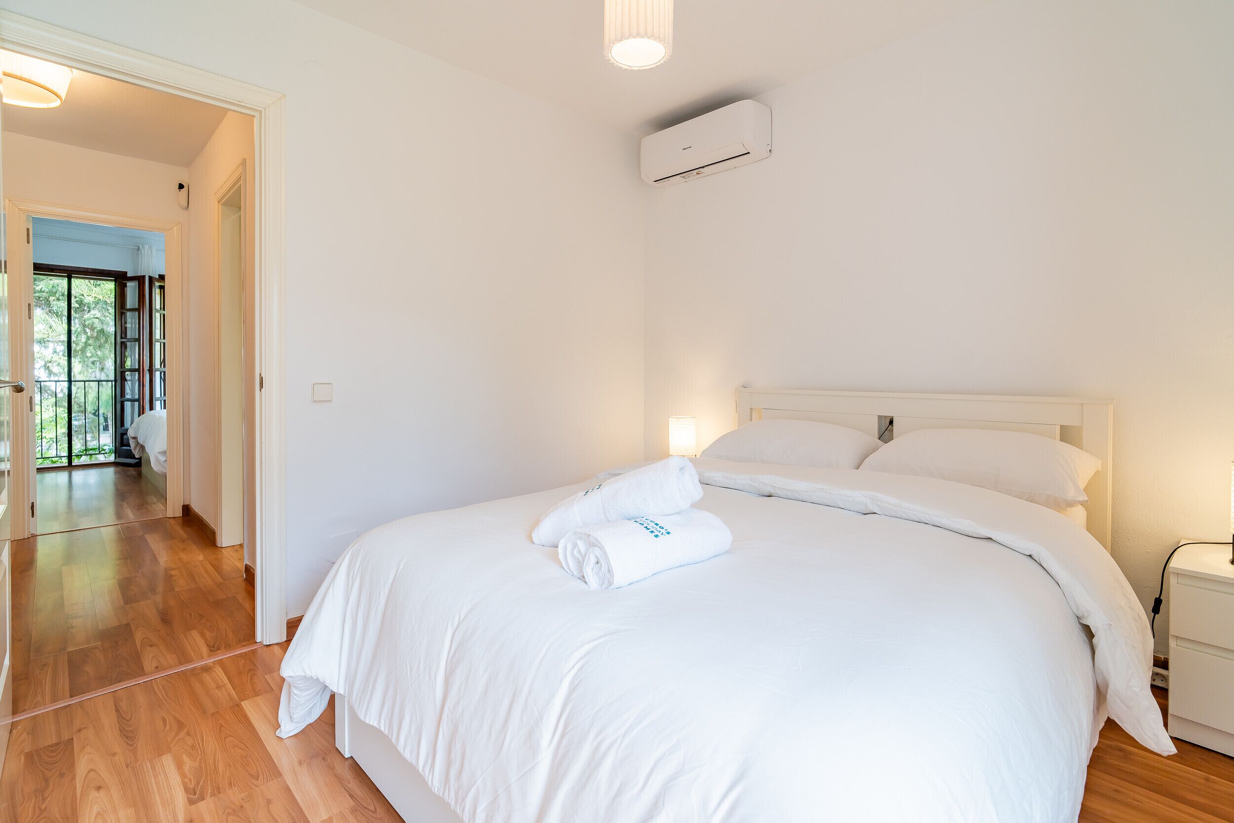 Et hotelværelse med en stor seng, et sengebord, en aircondition og udsigt til en balkon.