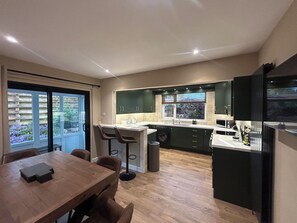 Eine moderne Küche mit Essbereich, einer Waschmaschine und Blick durch das Fenster.