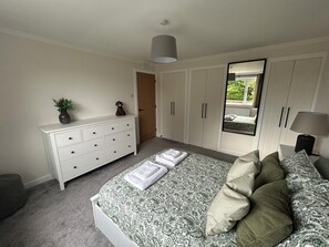 Ein Schlafzimmer mit Bett, Schminktisch, Spiegel und einem Fenster mit Blick.