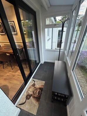 A modern interior with a glass door leading to a patio area, a bench, and a rug with a cat design. - Newly renovated cosy coastal retreat within walking distance of village pub! (Kippford)
