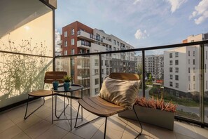 A balcony with two wooden chairs, a small table, and a potted plant. - Spacious Flat with a Balcony | Parking | Air-conditioning (Warszawa)