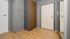 Une pièce aux murs gris, avec une armoire en bois, une porte blanche et un plancher en bois.