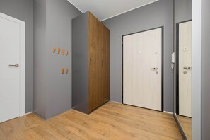 A room with grey walls, a wooden wardrobe, a white door, and a wooden floor. - Spacious Flat with a Balcony | Parking | Air-conditioning (Warszawa)