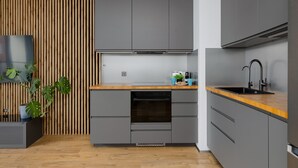 Une cuisine moderne avec des meubles de couleur grise, un plan de travail en bois et un four encastré.
