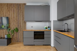 A modern kitchen with grey cabinetry, a wooden countertop, and a built-in oven. - Spacious Flat with a Balcony | Parking | Air-conditioning (Warszawa)